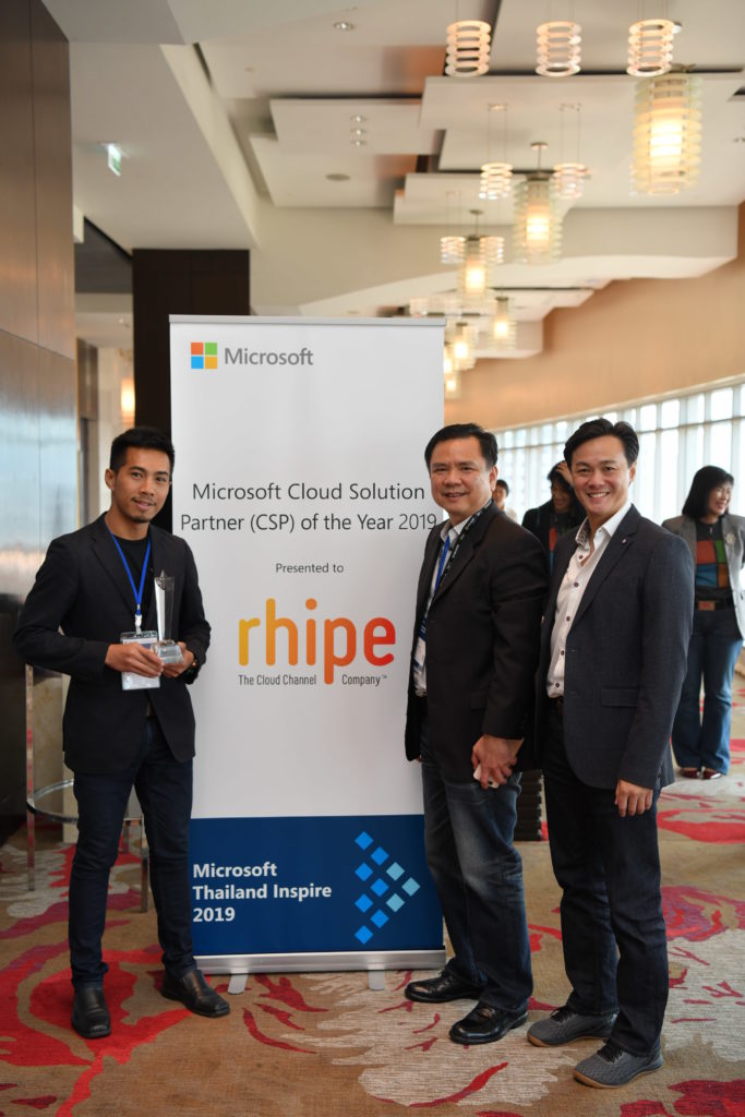 Executives and award in front of signage