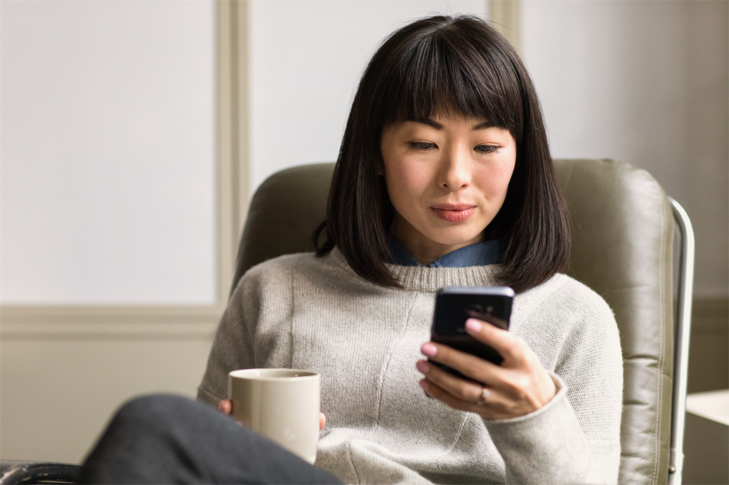 Woman sitting back and using a smartphone