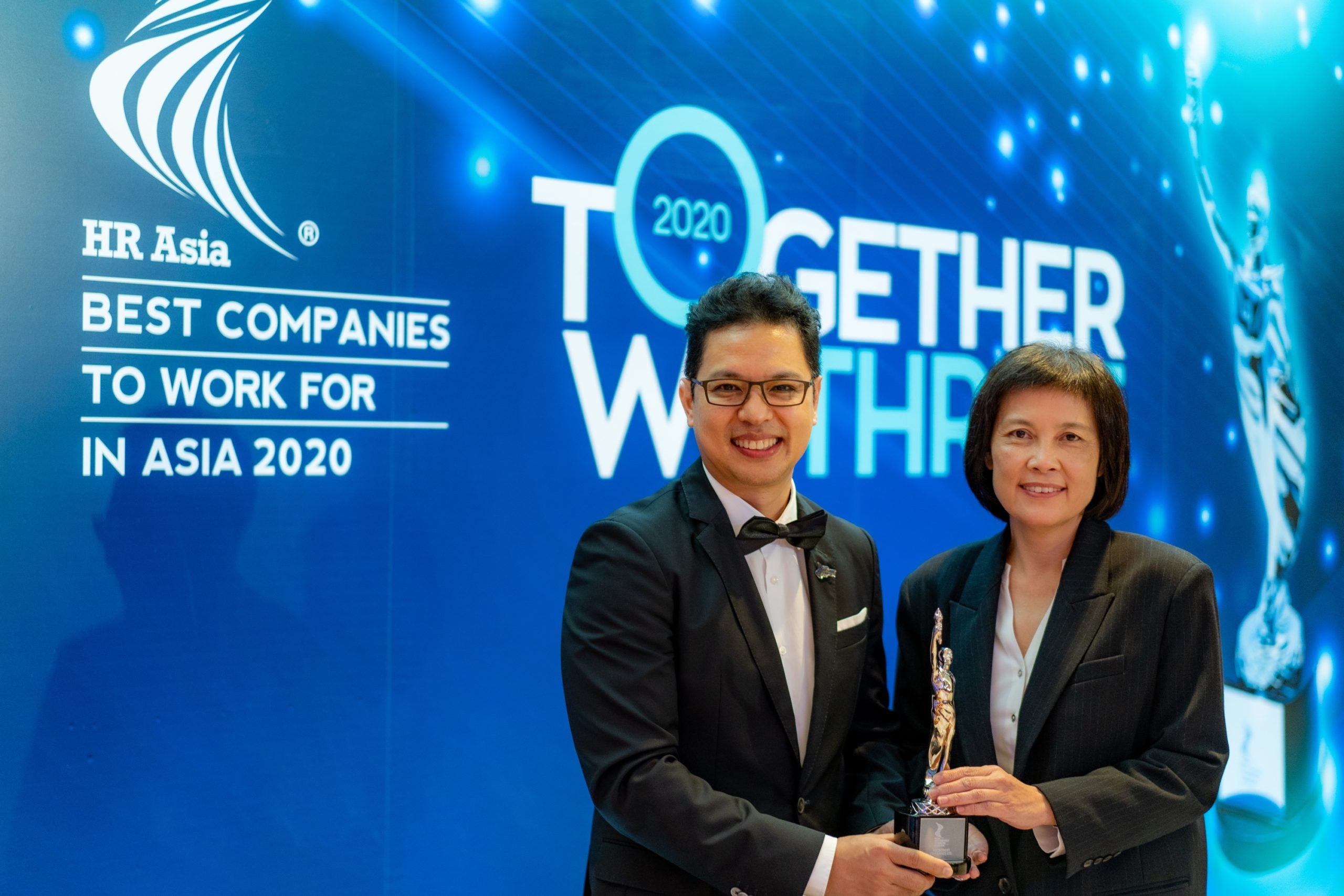 Man and woman in formal attire holding an award trophy