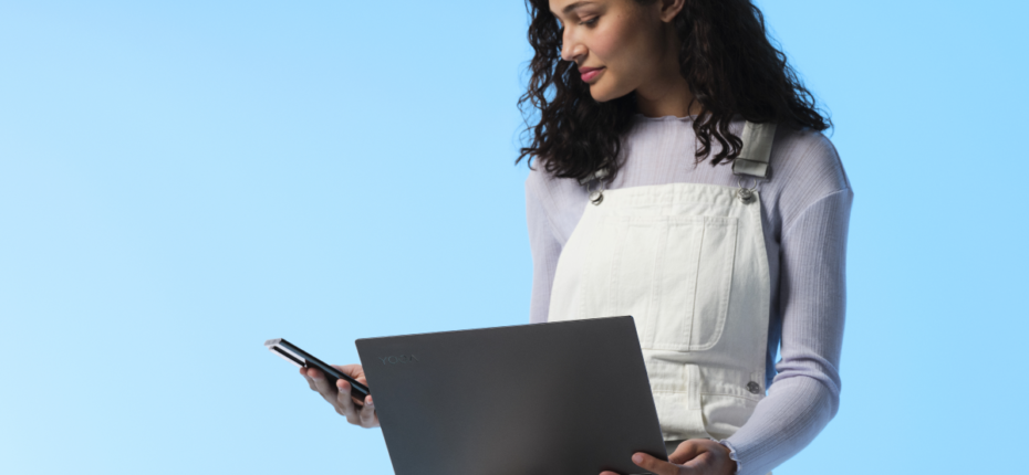 Woman holding a laptop and looking at a smartphone