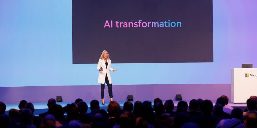 A woman standing on a big stage presenting to an audience