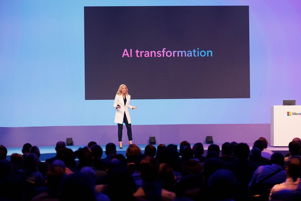 A woman standing on a big stage presenting to an audience