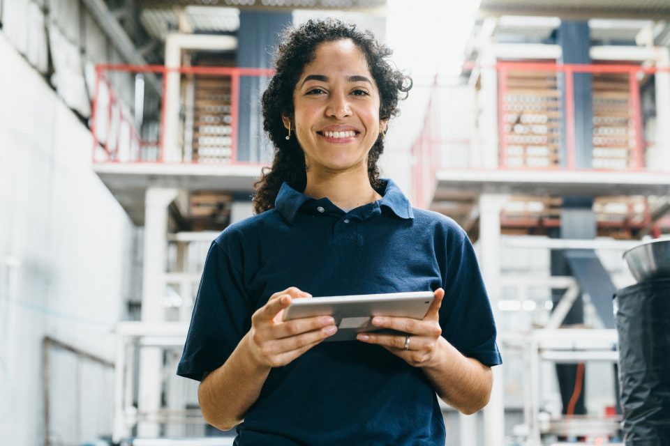 A woman in a factory holding a smart device in her hands