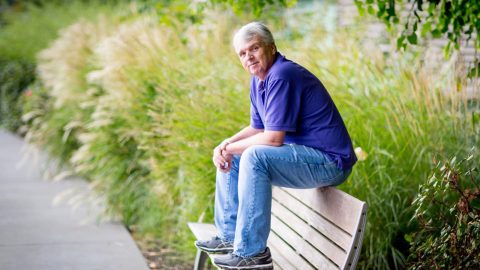 David Heckerman sits on the back of an outdoor bench