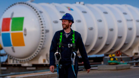 Spencer Fowers walks in front of the Project Natick underwater datacenter in the background