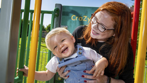 A woman plays with a toddler in a playground