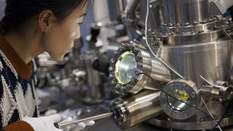 A woman looks into a piece of quantum material lab equipment