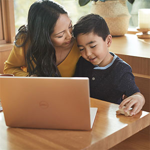 young boy works on computer with his mother