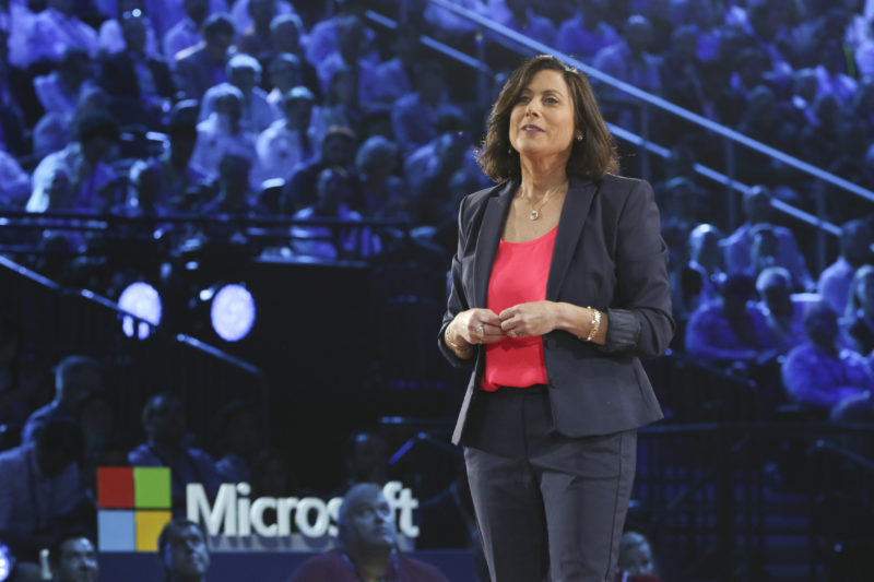 A woman stands on stage presenting.