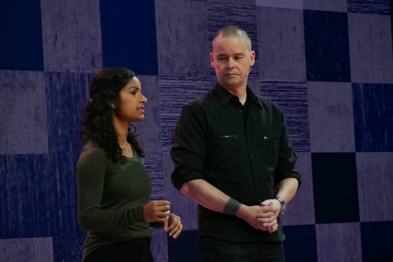 A woman and a man stand on stage speaking