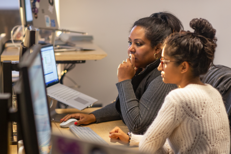 duas mulheres mexendo no mesmo computador