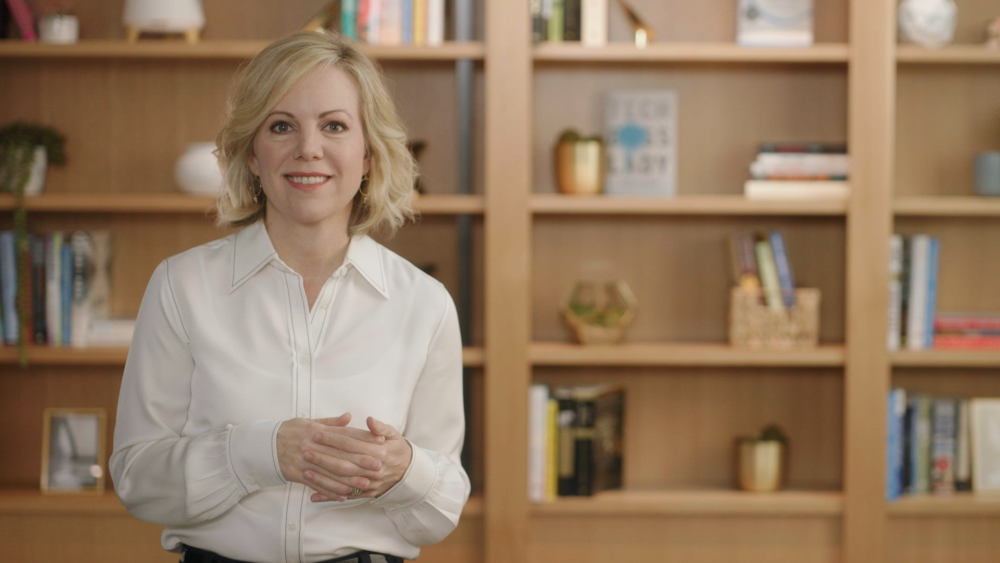 Woman in white with bookshelves in background