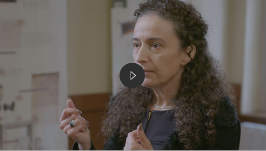 mulher de cabelo cacheado falando e mexendo as mãos