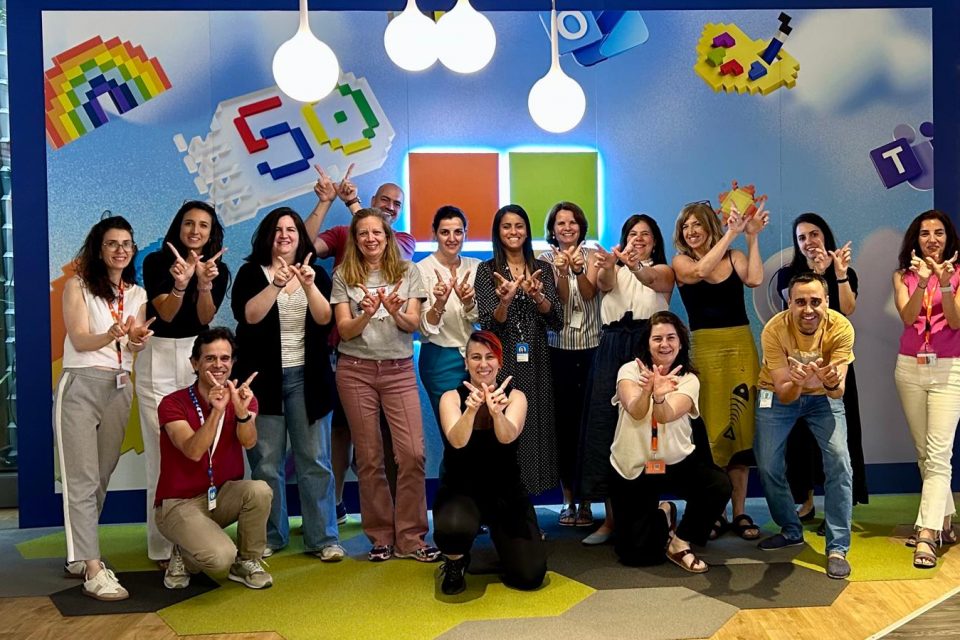 Foto grupal de mujeres delante de una pared tematizada con el 50 aniversario de Microsoft