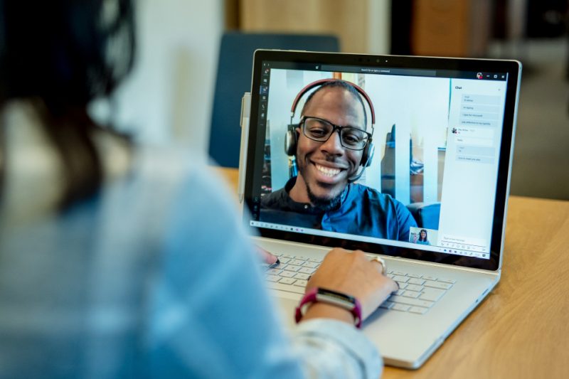 A person uses a laptop and the screen shows a man smiling