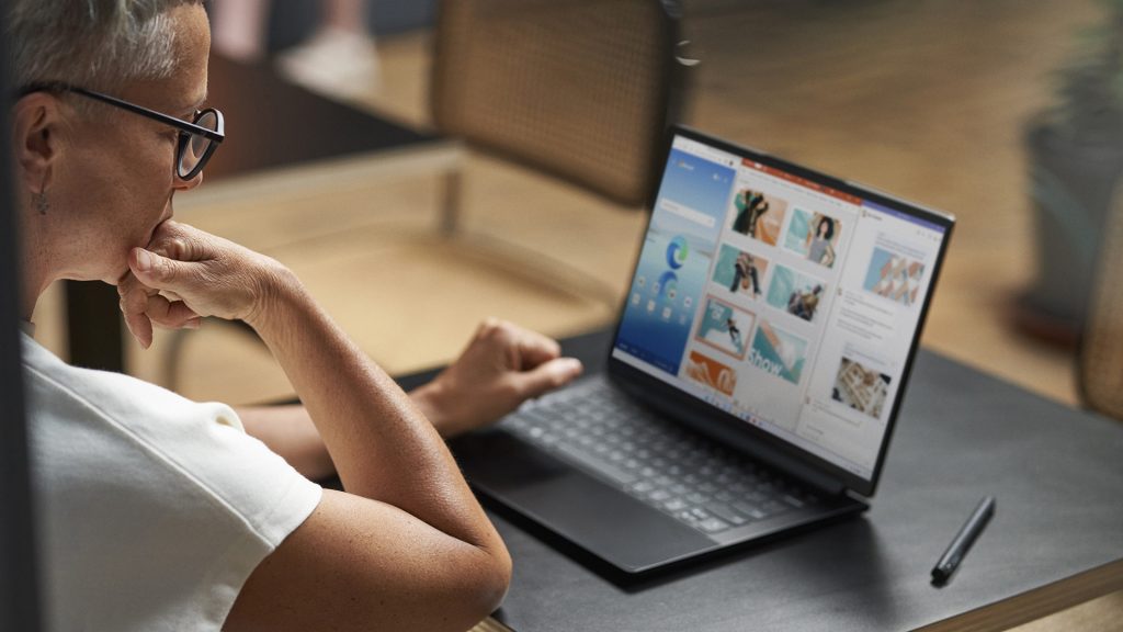 A woman sits at a desk with a laptop