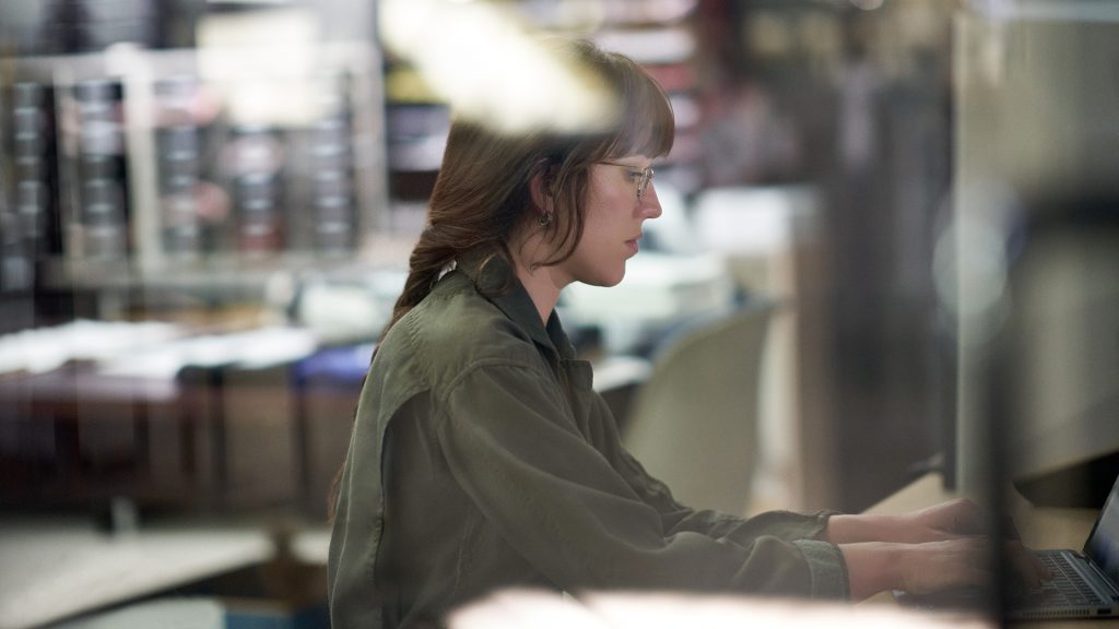 A woman works at a desk on her laptop