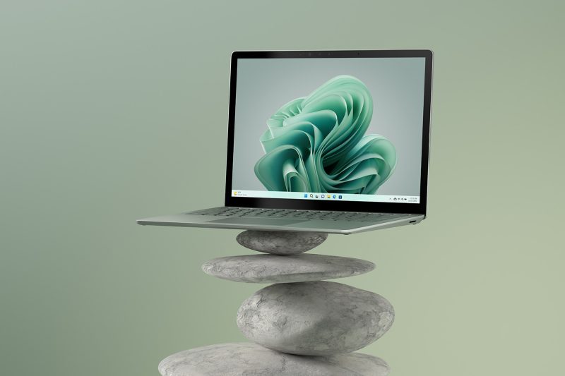 An opened laptop balances on top of a pile of stones.
