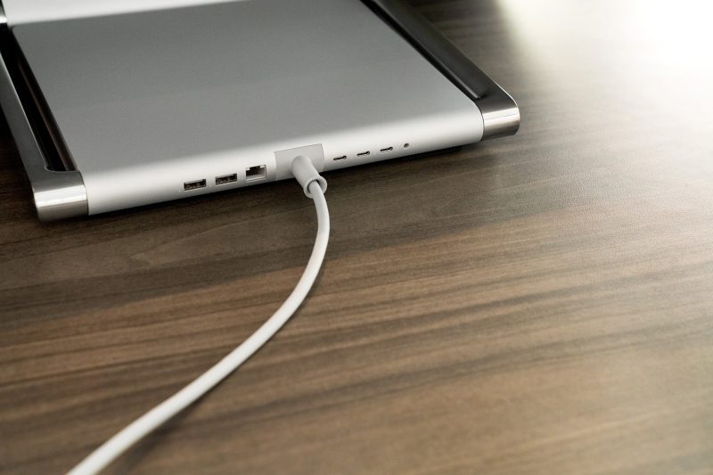 The base of an all-in-one computer sits on top of a table with its power cord plugged in.