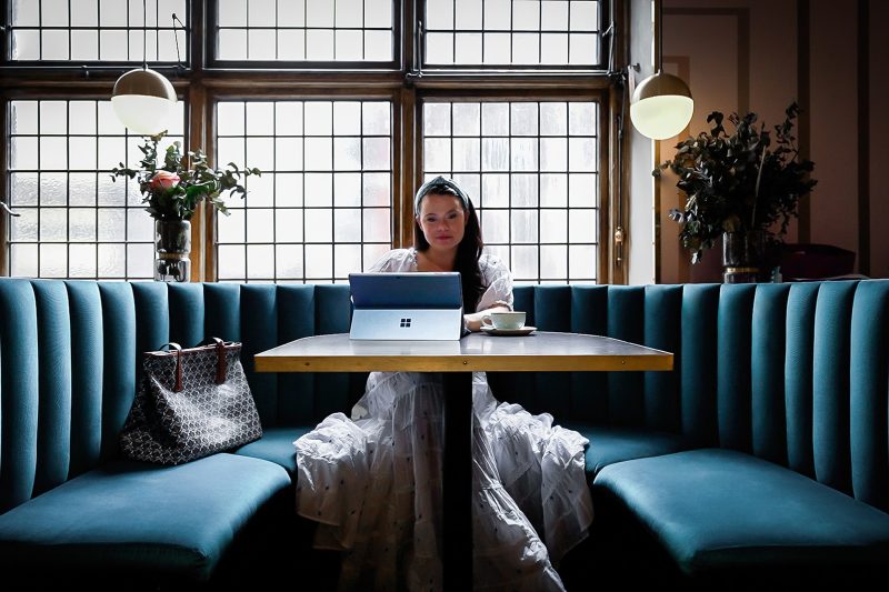 A person sits in a booth at a restaurant using their computer.