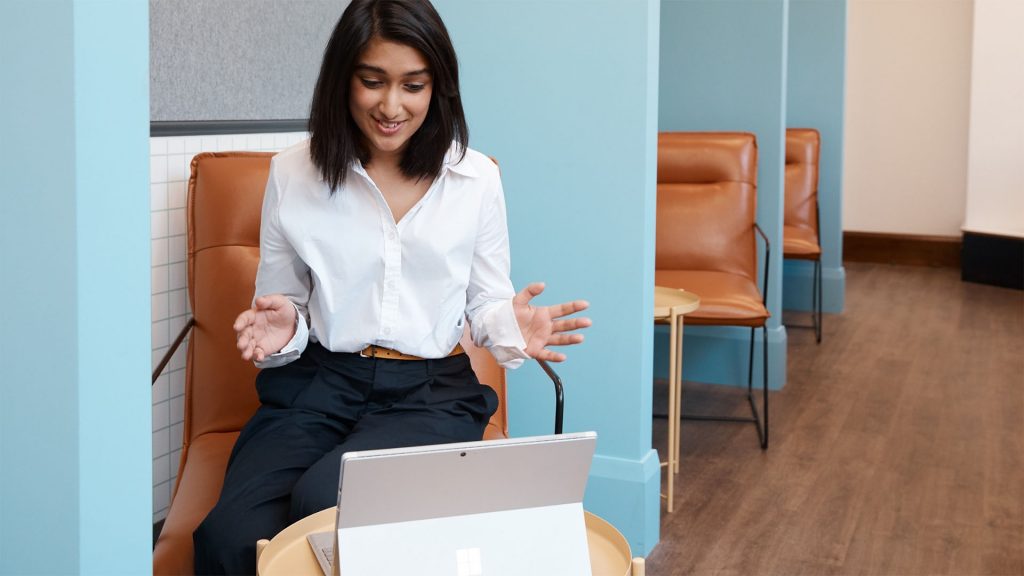 woman has hands up while looking at a surface device