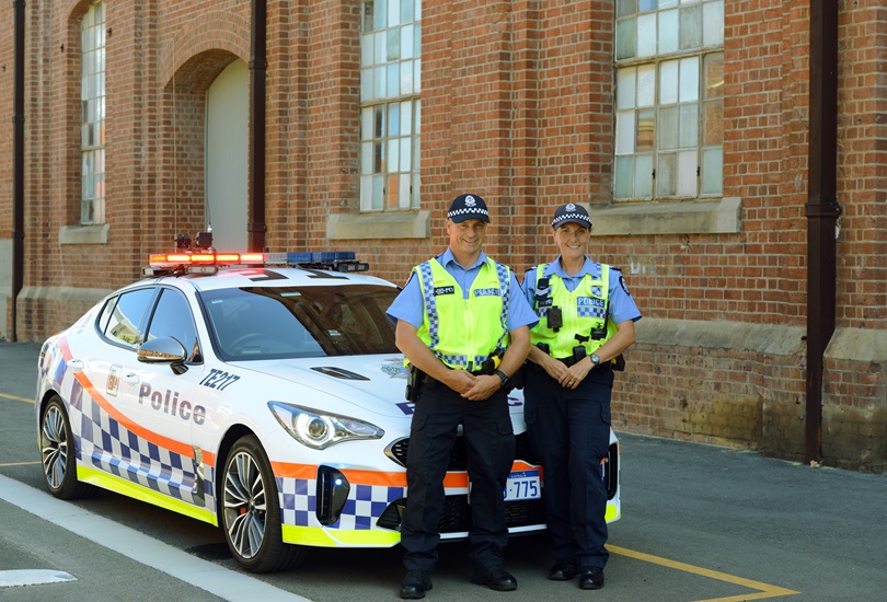 Police officers standing infront of police car