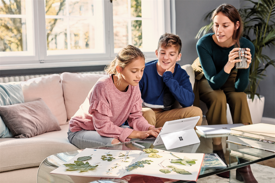 Image of mum watching son and daughter on laptop