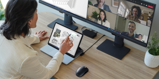 Adult female holding a Surface Slim Pen 2 while sitting at a desk.