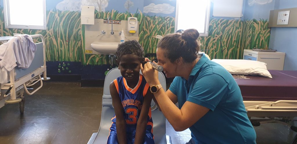 Health worker performing an ear test for an Aboriginal child