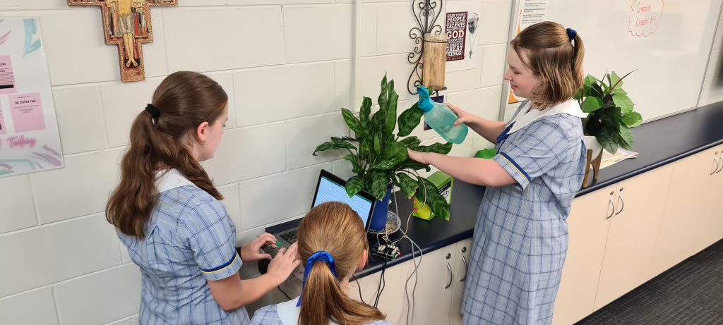 Three female students watering a plant