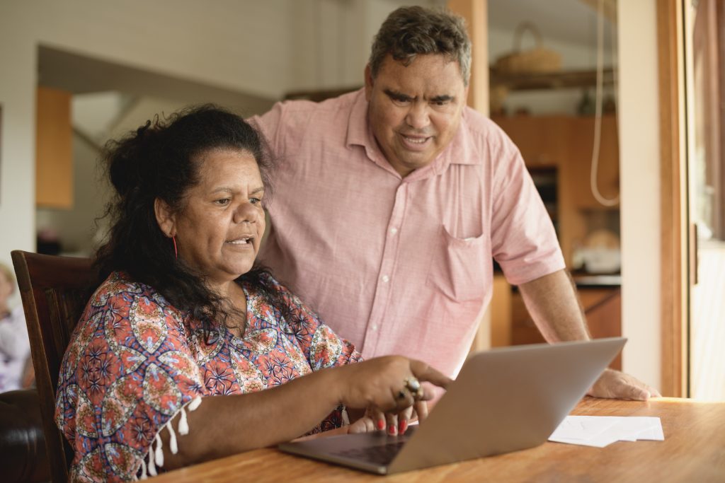 Mature couple using laptop with woman pointing