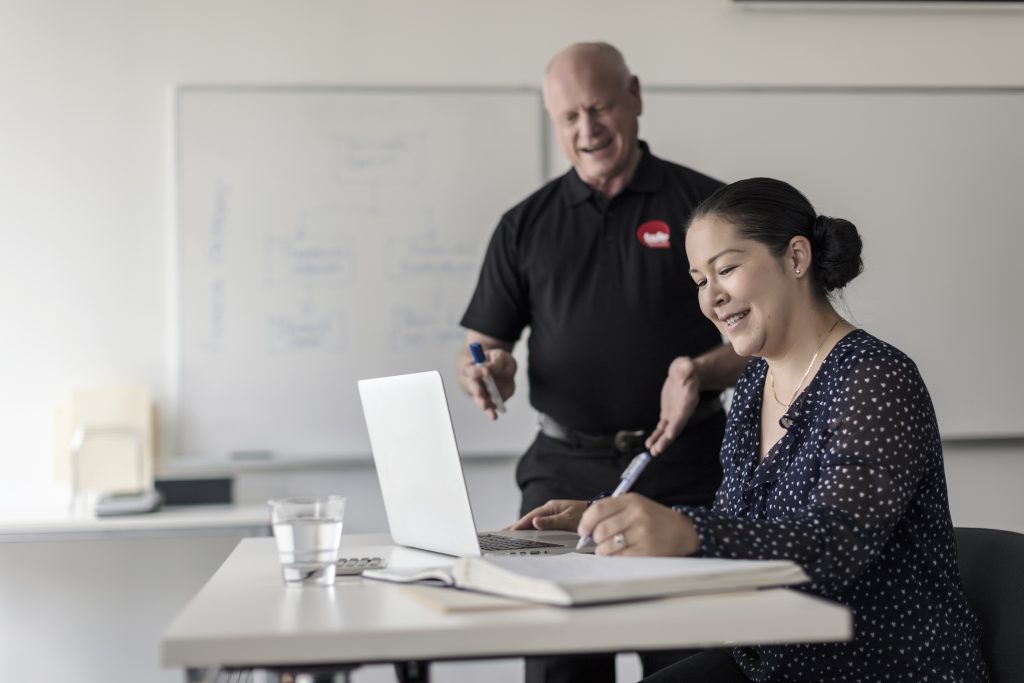 Male teacher assisting a student using a laptop