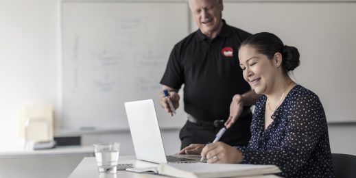 Male teacher assisting a student using a laptop