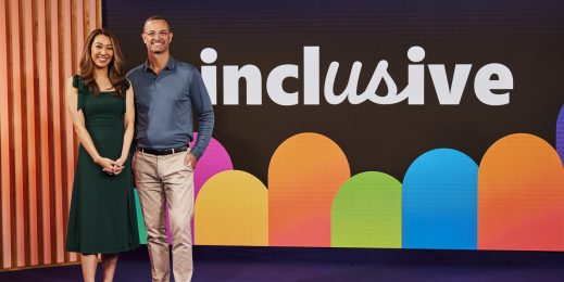 Adult female and male standing side by side infront of the inclusive event sign