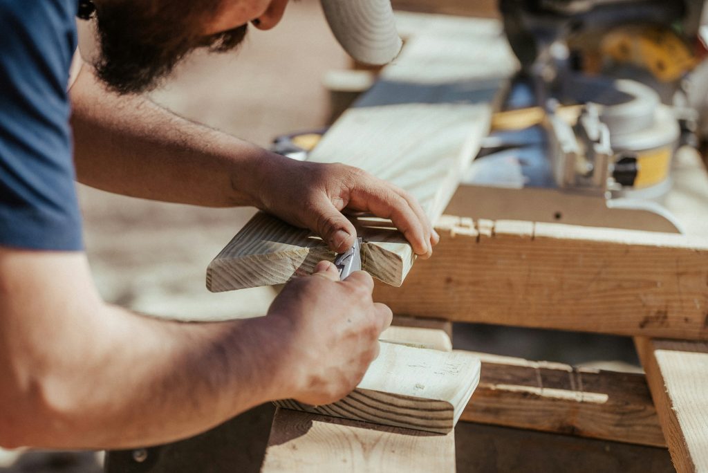 A Caucasian man carving a wooden plank