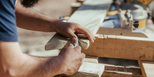 A Caucasian man carving a wooden plank