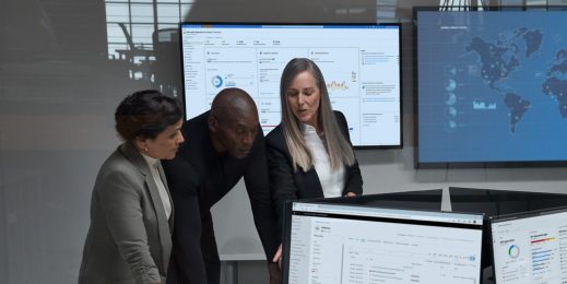 Three people standing in a security operations cetnre with screens representing cyber threat landscape