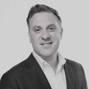 Portrait photo of Adam Riching, in black and white tone.