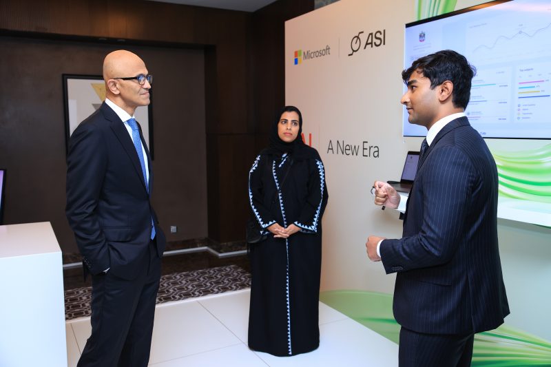 Microsoft Chairman and CEO Satya Nadella interacts with a man and woman at an event booth