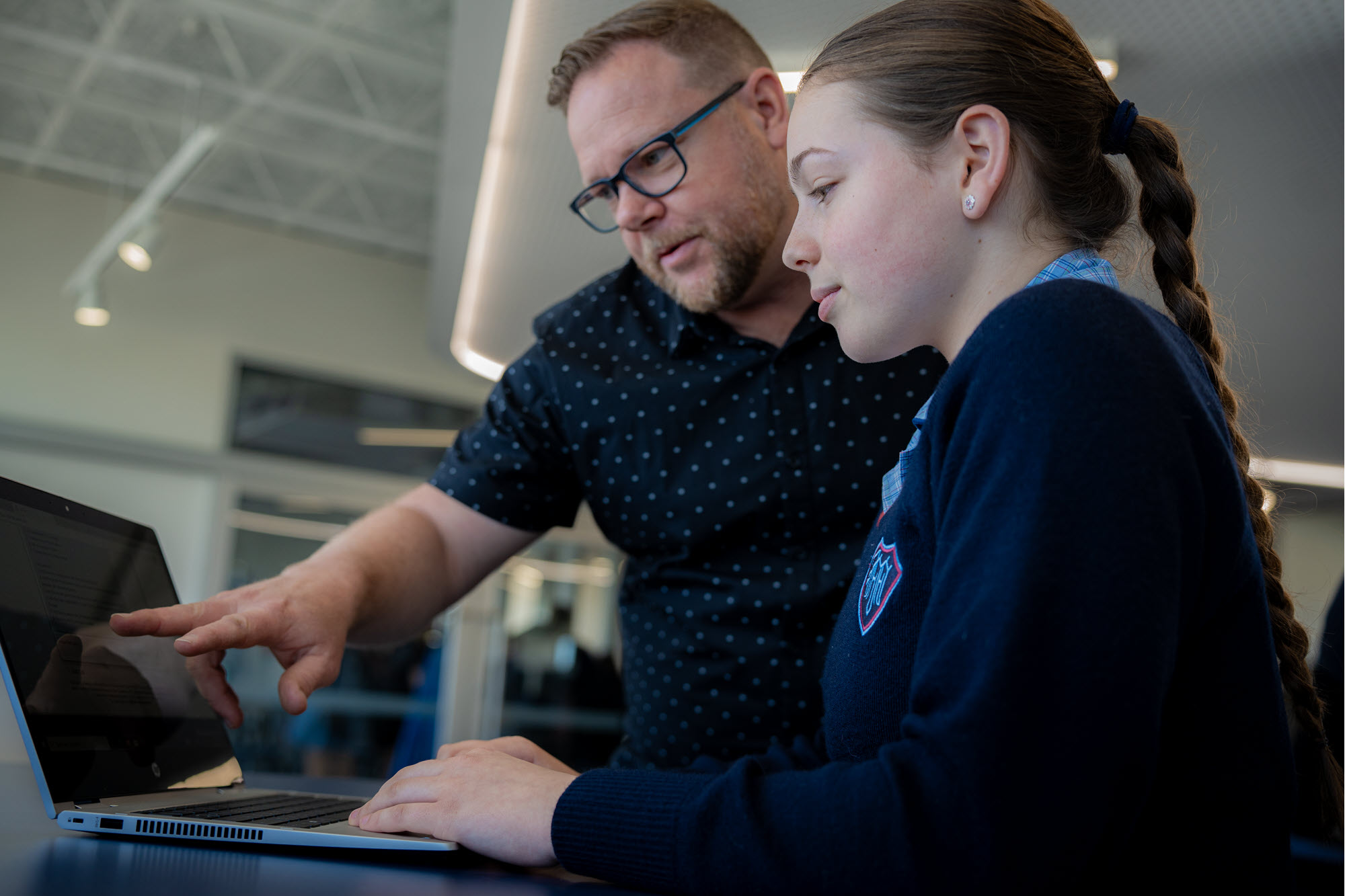 Two people look at a laptop screen