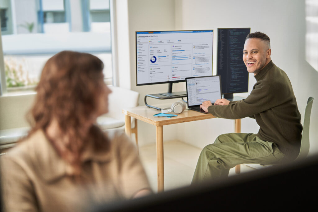 A man types on a laptop and smles
