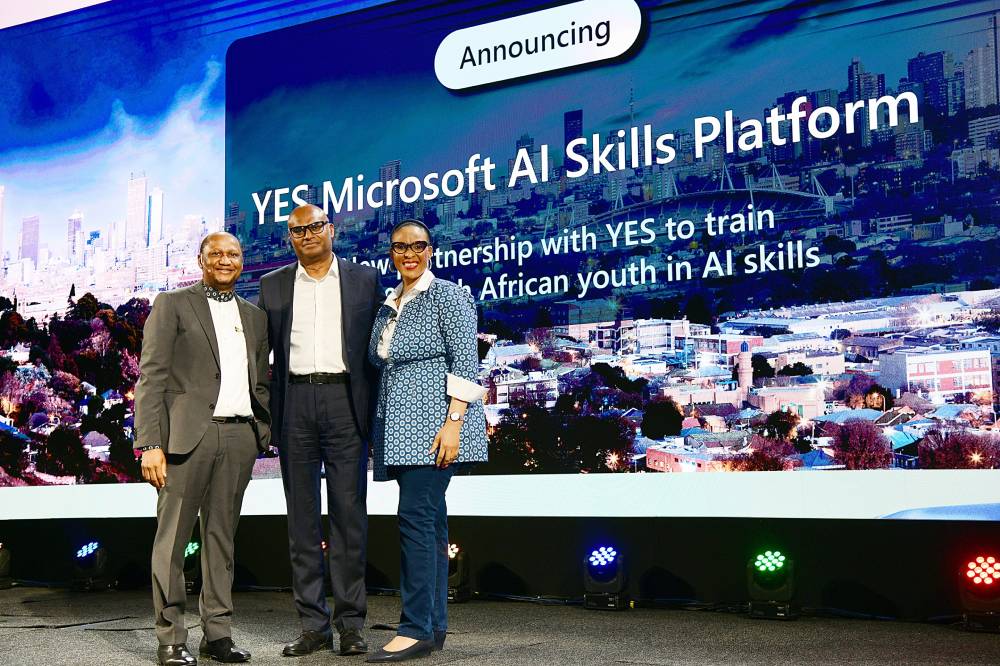 Three people stand smiling on a stage