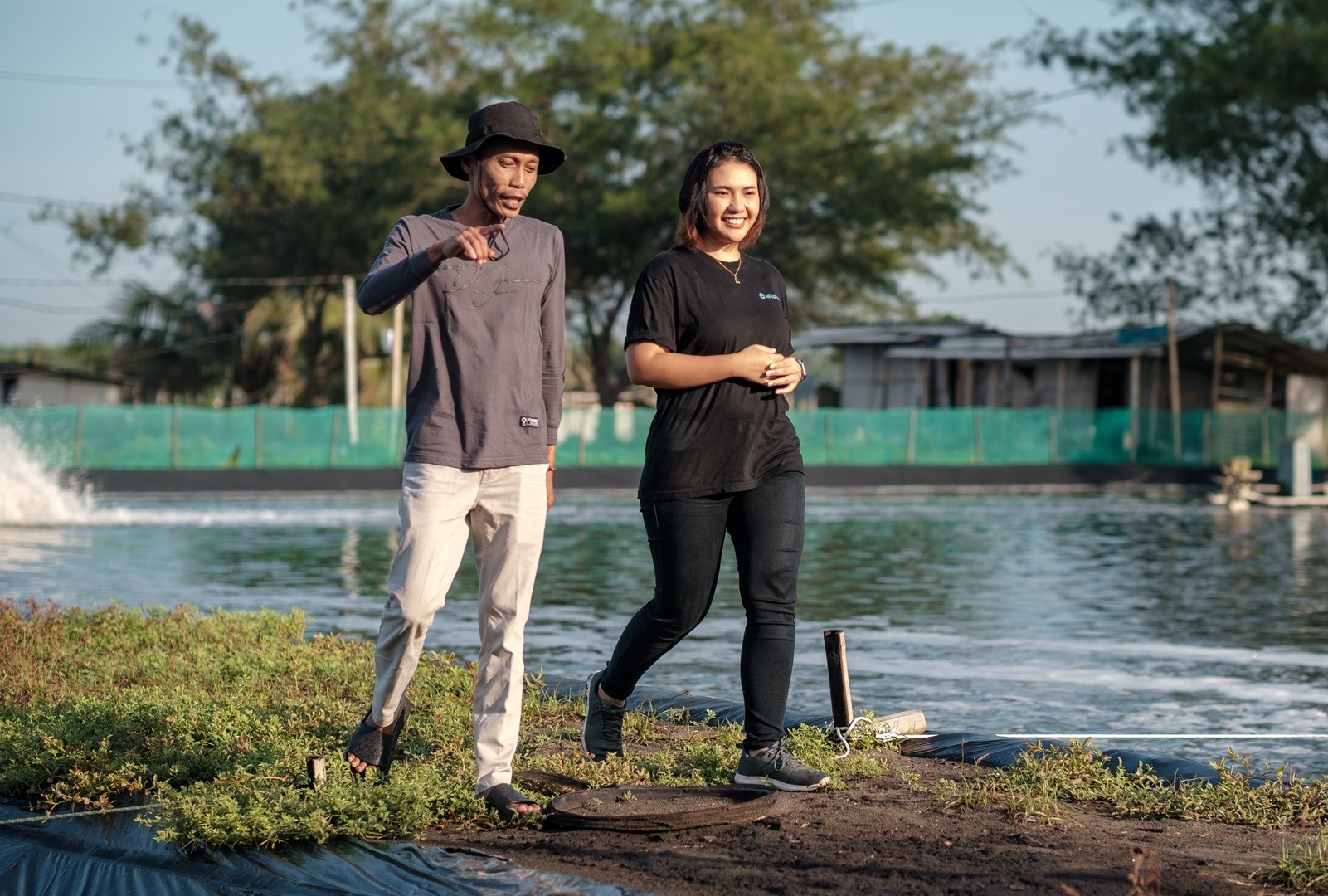 Man and woman walking along a pond in a shrimp farm