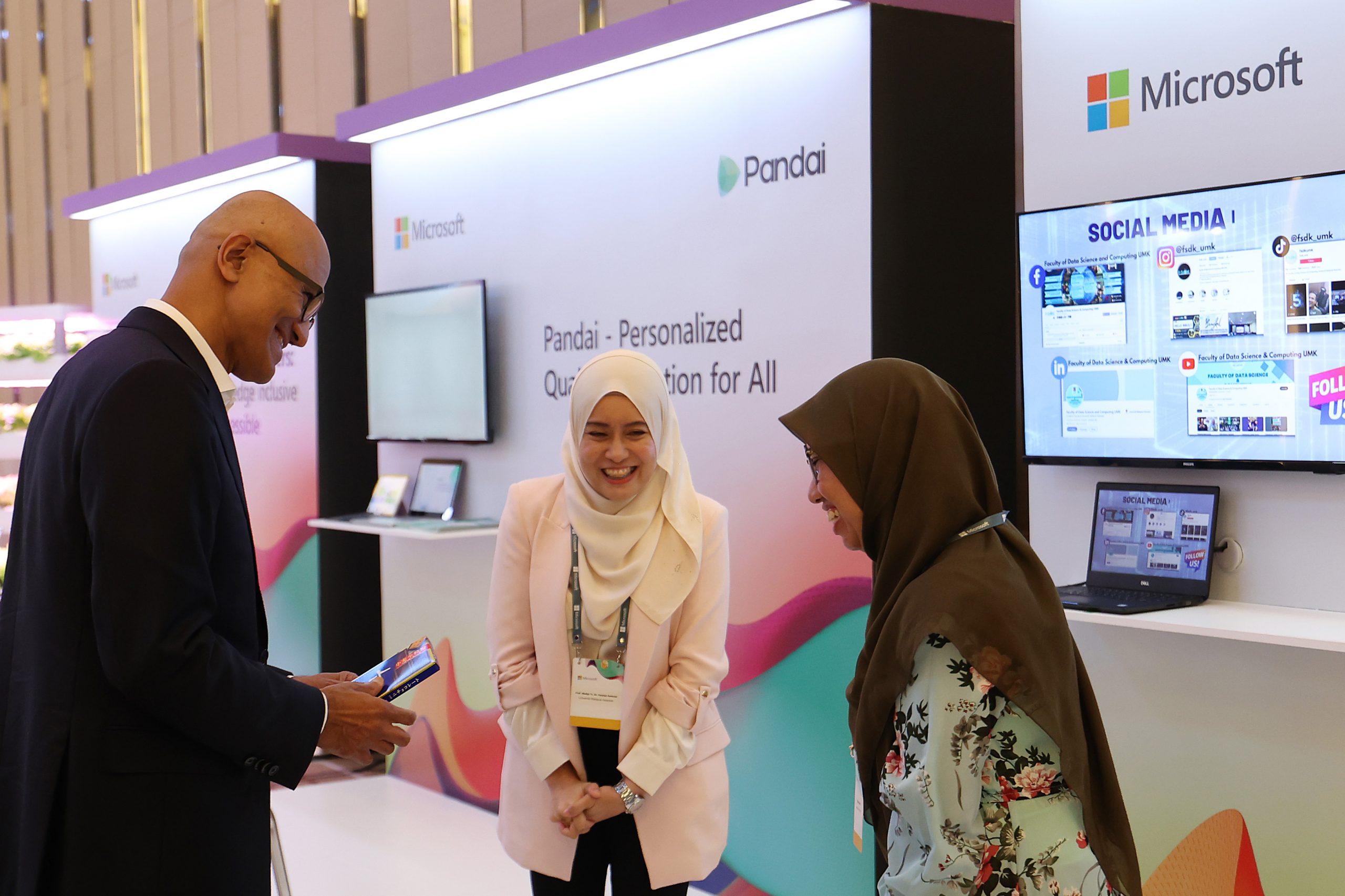 Man and two women in conversation at a conference booth
