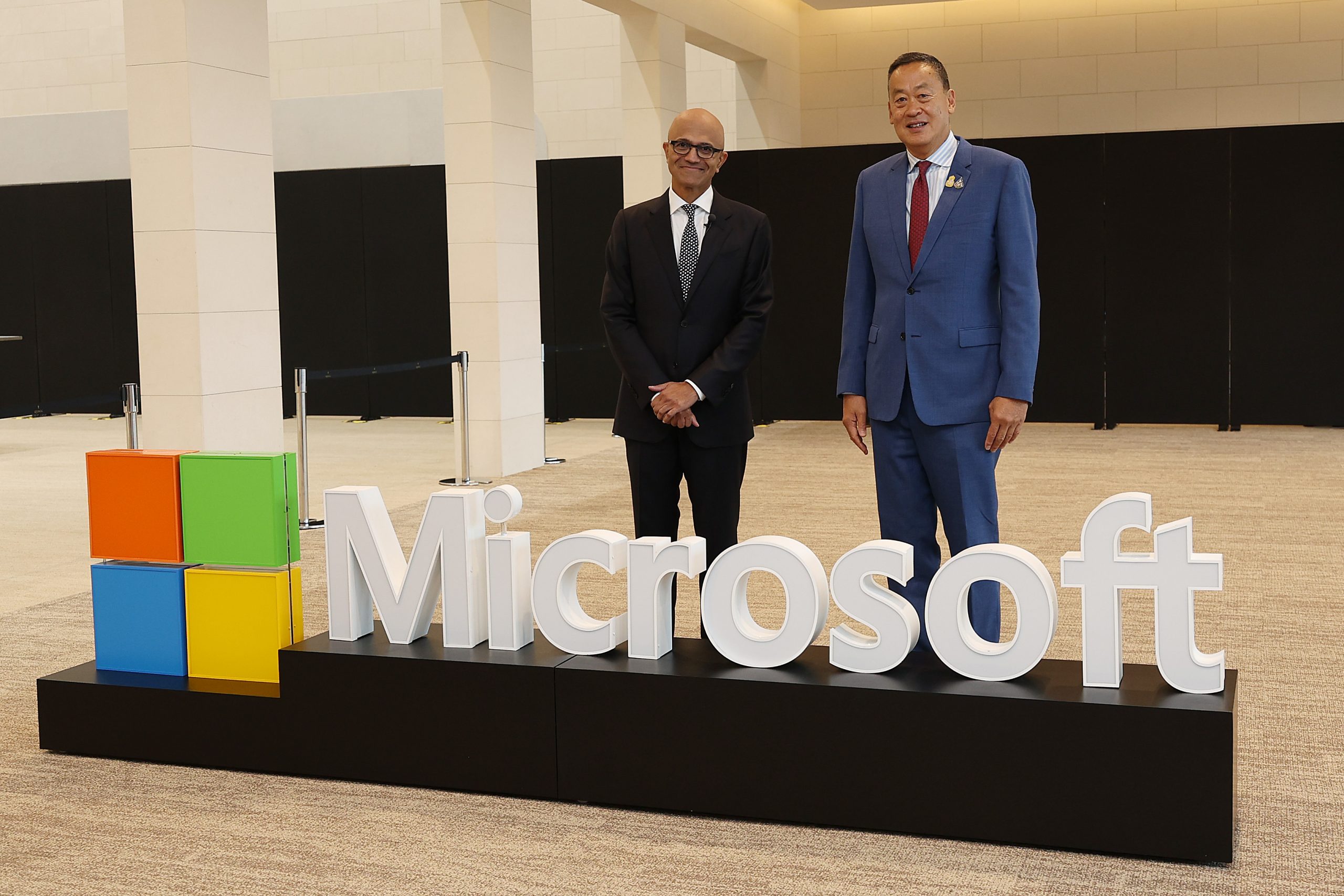 Two men standing behind the Microsoft logo