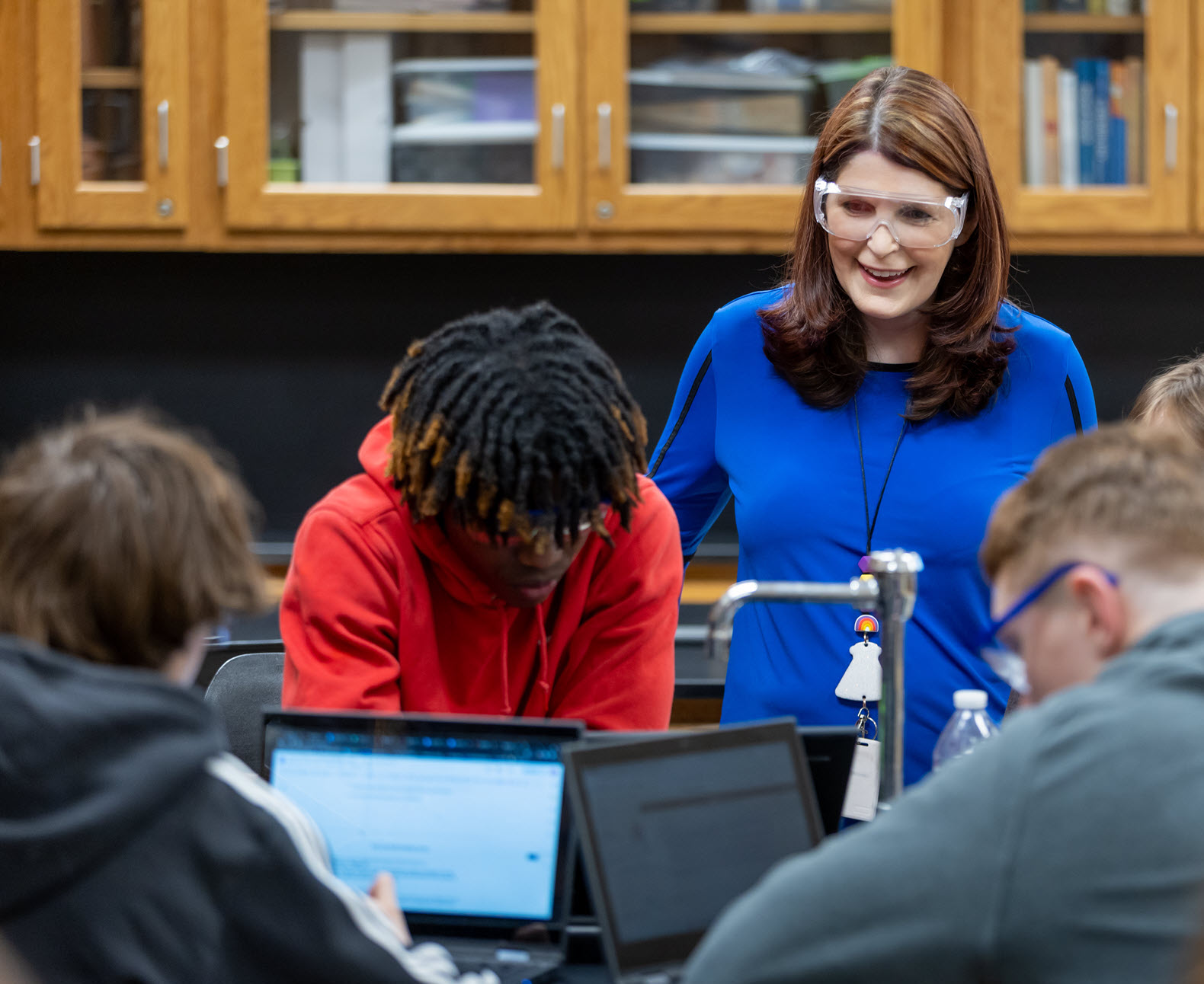 A female chemistry teacher works with a group of students in a classroom setting