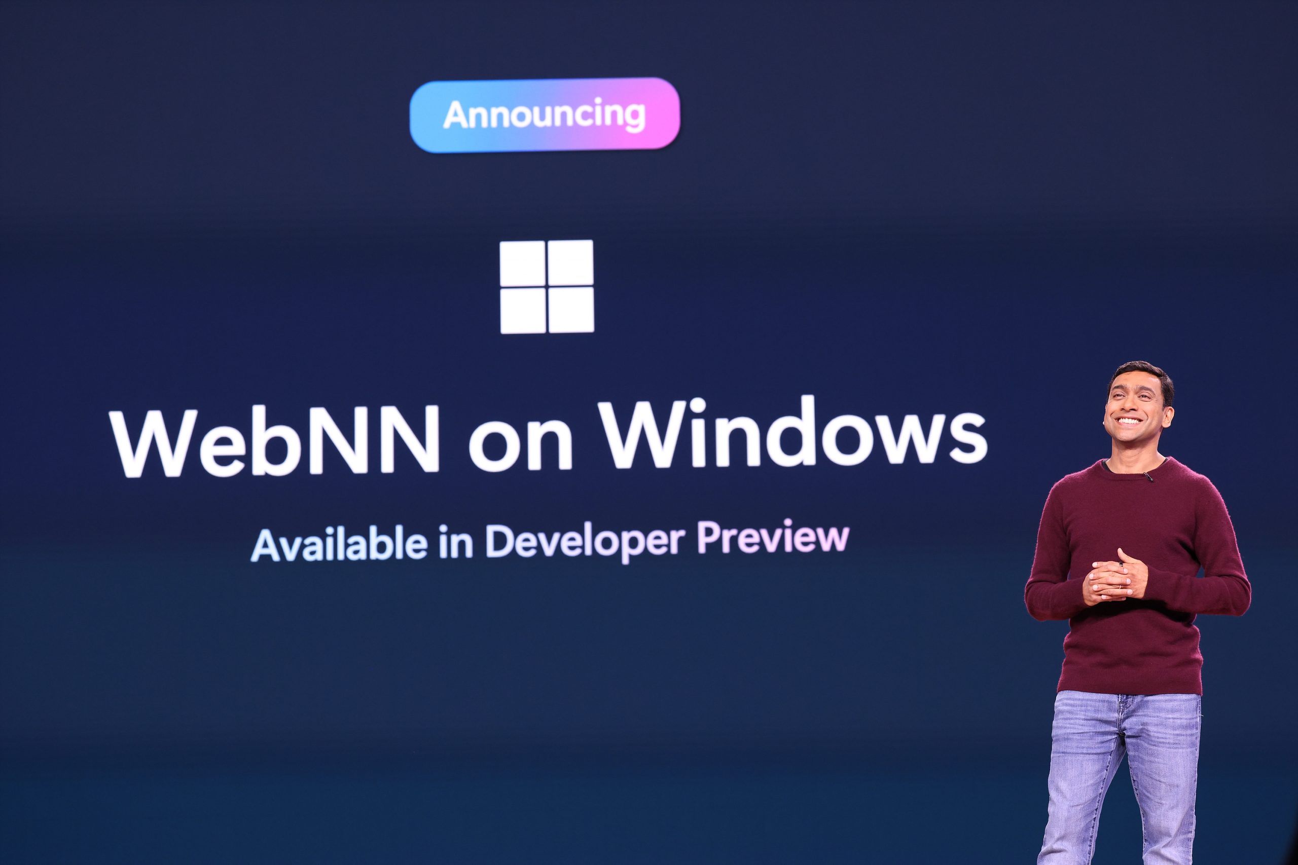 A man standing on stage, with text on a screen behind him that reads, "Announcing WebNN on Windows. Available in Developer Preview."