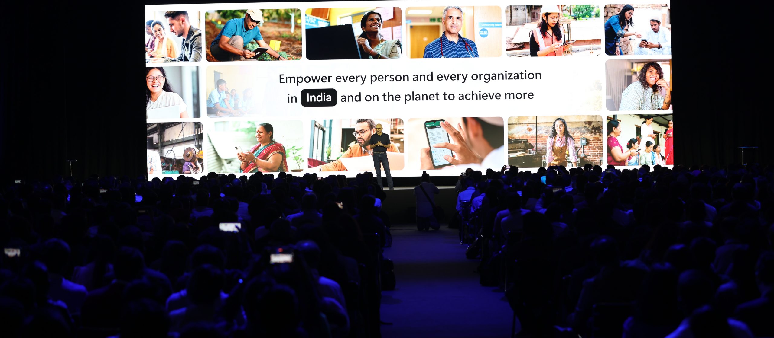 man on stage with backdrop that says empower every person and every organisation in India and on the planet to achieve more