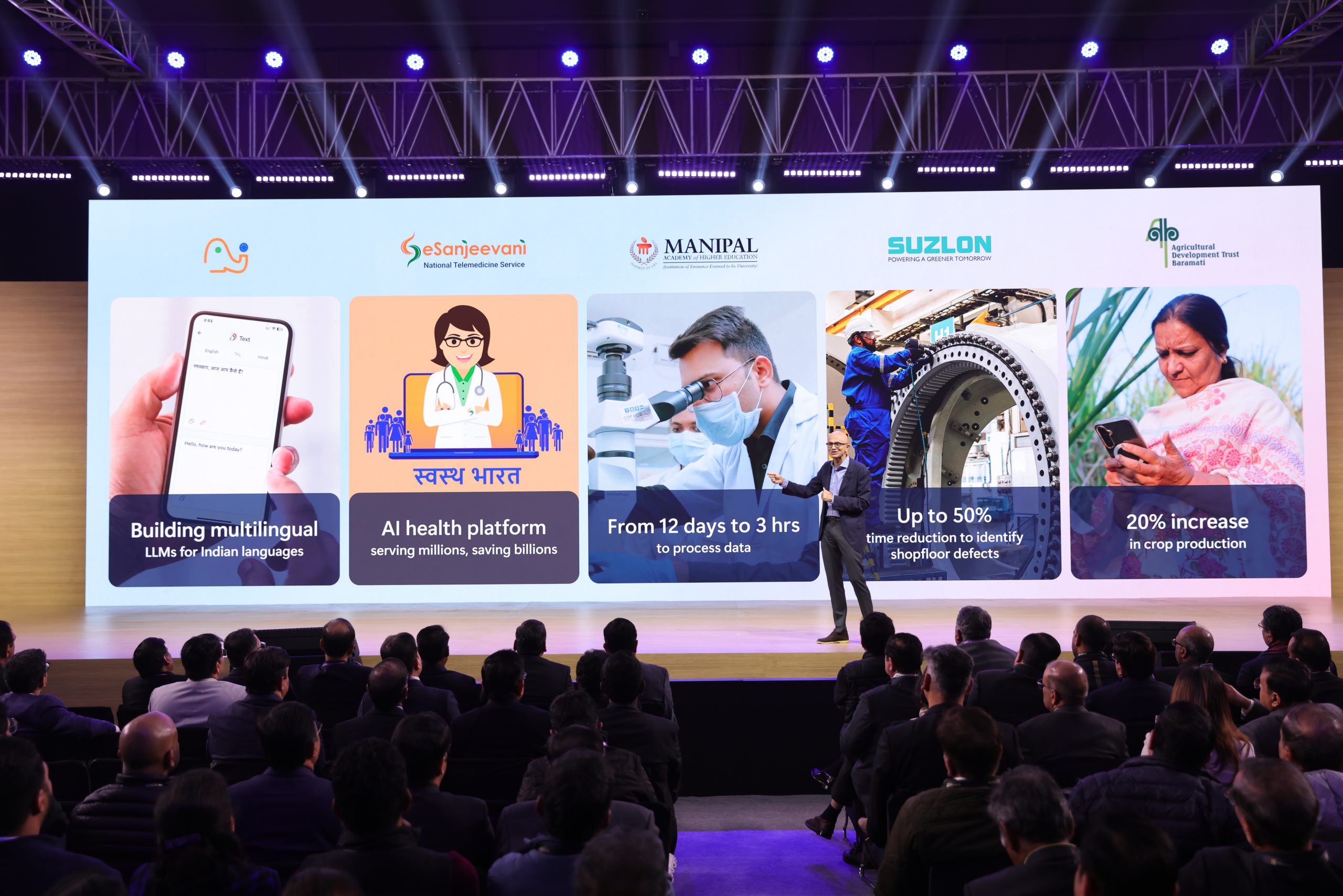 A man on stage with various images and logos on the backdrop