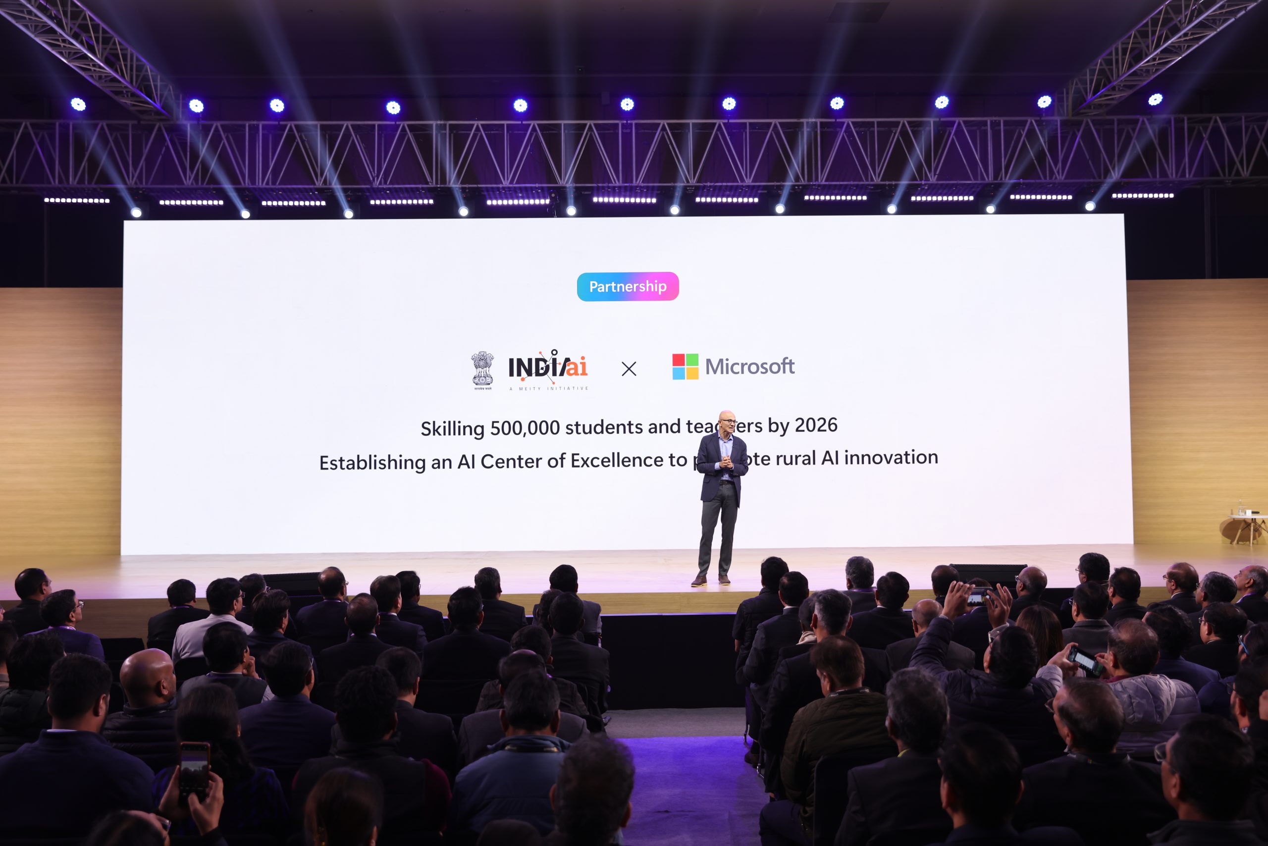 man on stage with backdrop that reads partnership IndiaAI X Microsoft, skilling 50,000 students and teachers by 2026
